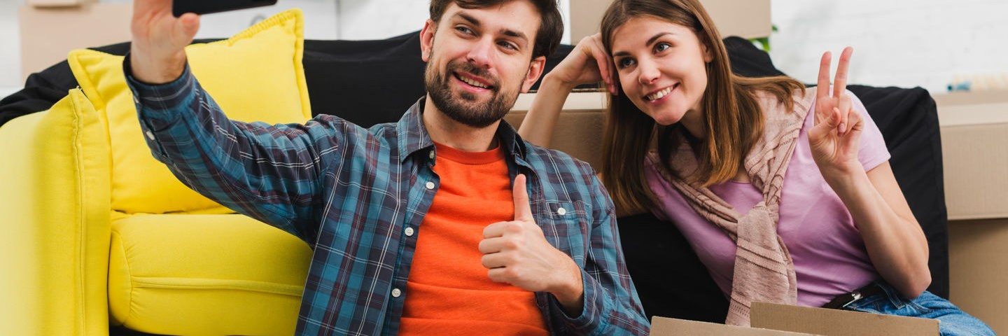 Apartment rental home couple taking selfie surrounded by boxes